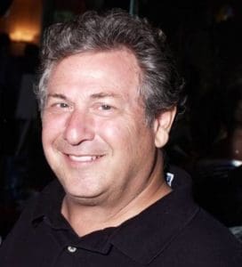 A man in a black shirt smiling for the camera.