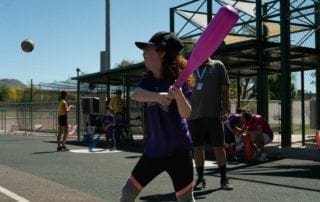 A girl swinging a bat at a baseball game.