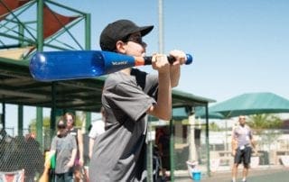 A boy swinging a bat at a baseball field.