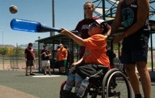A boy in a wheelchair is throwing a baseball.