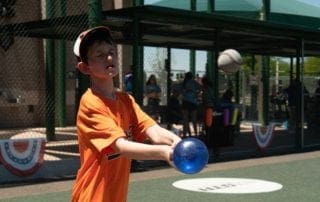 A young boy is throwing a ball at a baseball field.
