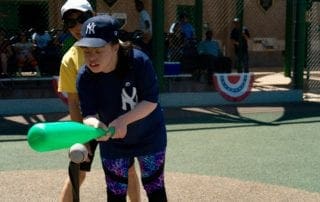 A girl is hitting a ball with a bat.