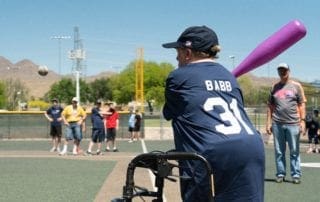 A woman in a wheelchair holding a baseball bat.