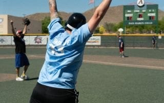 A man throwing a baseball in the air at a baseball field.