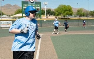 A man wearing a blue baseball hat is running on a baseball field.
