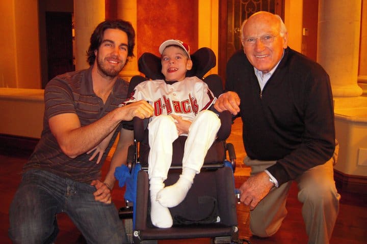 Three men posing with a boy in a wheelchair.