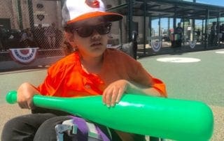 A boy in a wheelchair holding a baseball bat.