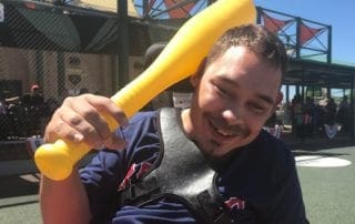 A man in a wheelchair holding a yellow baseball bat.