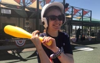 A woman wearing a helmet and holding a baseball bat.