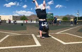 A girl doing a handstand on a baseball field.