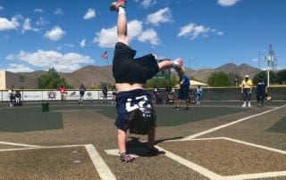 A boy doing a handstand on a baseball field.