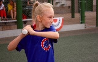 A girl swinging a bat at a ball.