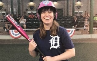 A woman holding a baseball bat and smiling.
