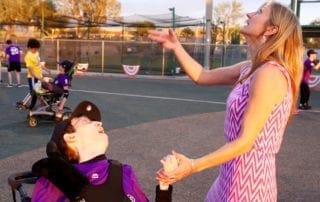 A woman in a wheelchair is reaching out to a boy in a wheelchair.