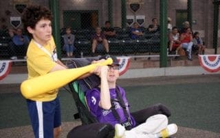 A boy in a wheelchair is hitting a baseball bat.