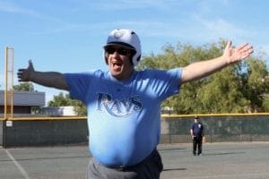 A man in blue shirt and helmet standing on baseball field.