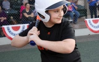 A young boy holding a baseball bat in front of a crowd.