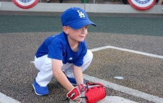 A young boy wearing a blue baseball catcher's mitt.