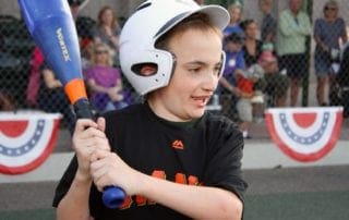 A young boy holding a baseball bat in front of a crowd.