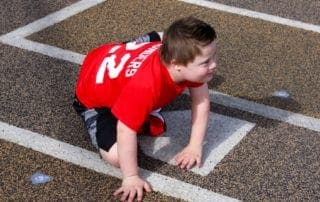 A young boy crouching down on a track.
