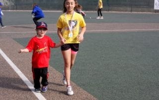 A girl and a boy walking on a tennis court.