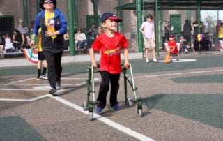 A young boy in a wheelchair on a baseball field.