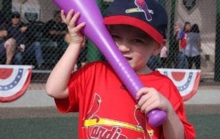 A young boy holding a purple bat.