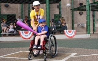 A woman in a wheelchair holding a baseball bat.