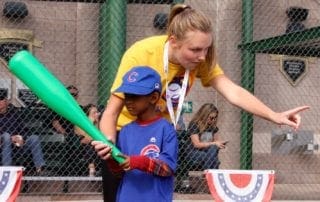A woman holding a bat with a young boy.