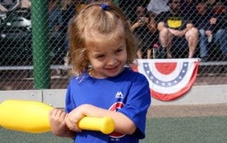 A little girl holding a yellow bat.