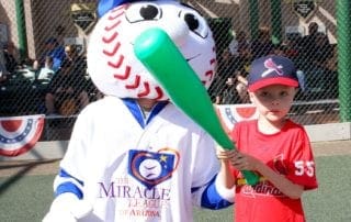 A boy is holding a baseball bat with a mascot.