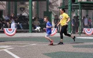 A woman is kicking a soccer ball with a young boy.