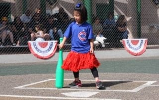 A girl holding a bat in a baseball field.