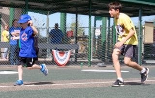 Two young boys running on a baseball field.