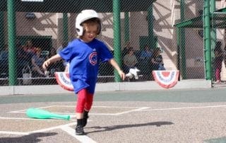 A young boy playing baseball with a bat and a green ball.