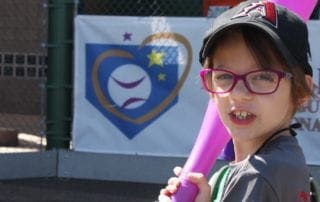 A young girl holding a baseball bat.