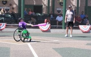 A boy in a wheelchair is hitting a ball on a baseball field.