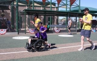 A boy in a wheelchair is playing a game of baseball.