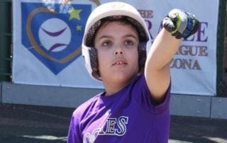 A young boy in a purple shirt is throwing a ball.