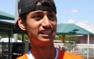A young man wearing an orange shirt and hat.