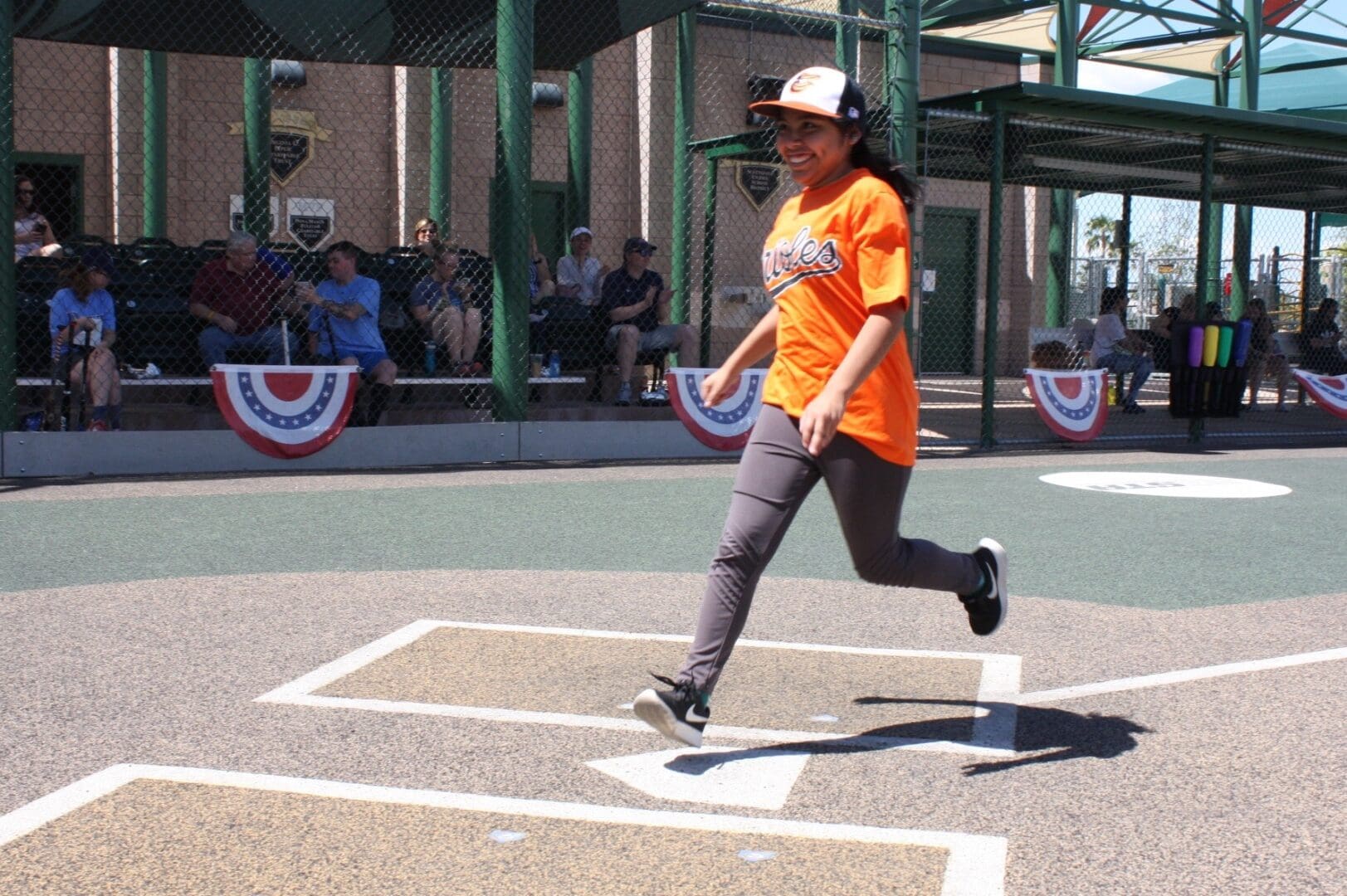 A girl is running on a baseball field.