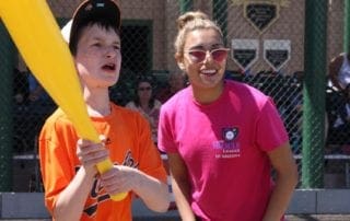 A young boy is holding a baseball bat while a woman smiles.