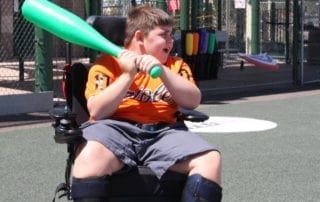 A boy in a wheelchair holding a baseball bat.