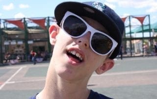 A boy wearing sunglasses and a hat.