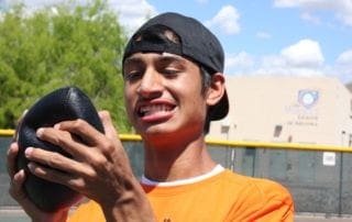 A young man in an orange shirt holding a black ball.