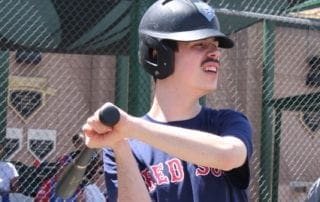 A man with a mustache swinging a bat.