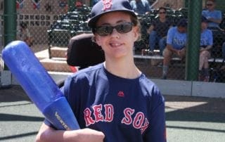 A boy in a red sox uniform holding a baseball bat.