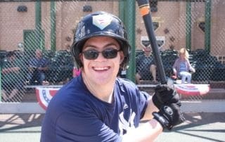 A young man holding a baseball bat and smiling.