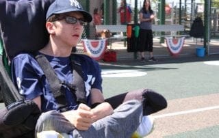 A boy in a wheelchair sitting on a baseball field.