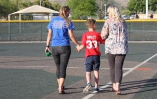 Two women and a boy walking on a baseball field.